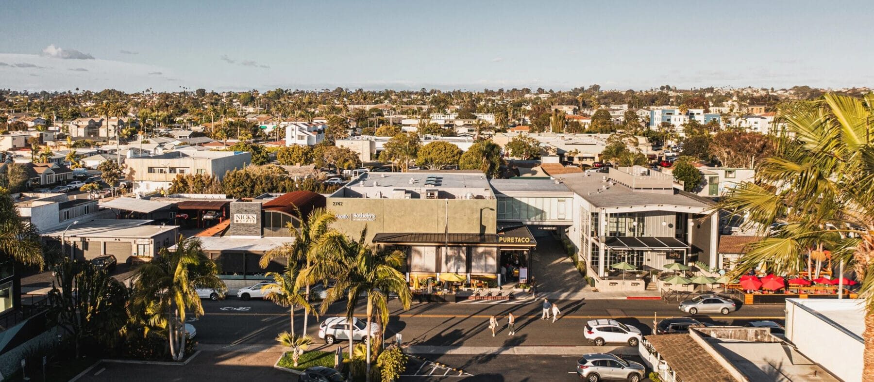 Aerial view of coastal storefronts featuring a variety of retail shops with palm trees surrounding