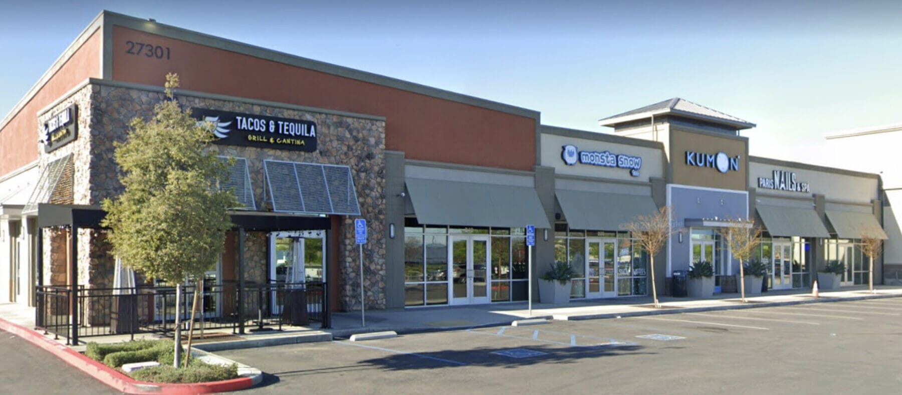 View of the shops at Center Pointe Shopping Center, multiple shops in a row and a tree in front.