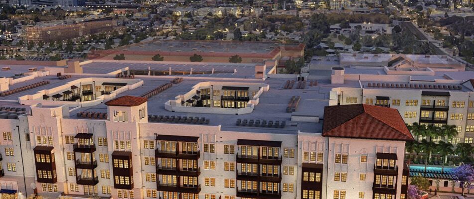 Several stories-high building with a sunset in the background. Building is white with some red tiling.