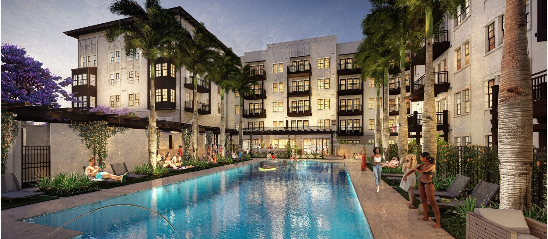 Several stories-high building with a sunset in the background. Building is white with some dark trim. Pool is in the foreground.