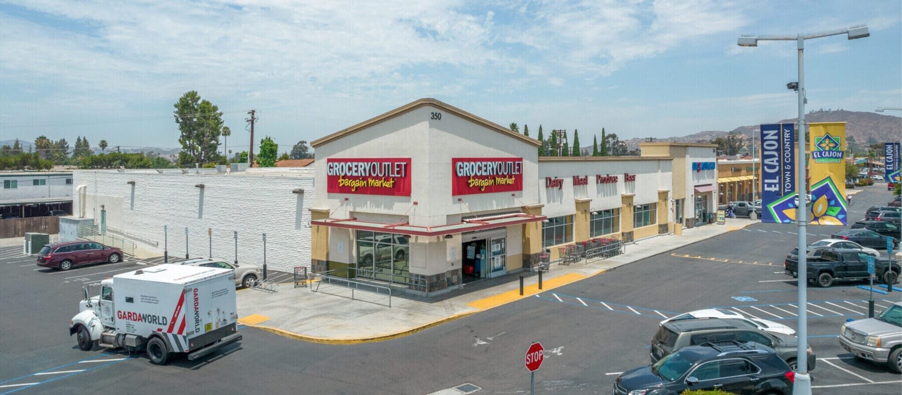 Former Grocery Outlet building at 350 N 2nd St viewed from the corner with a large parking lot in front. To the right are Eyeglass World and other shops in El Cajon Town & Country shopping center.
