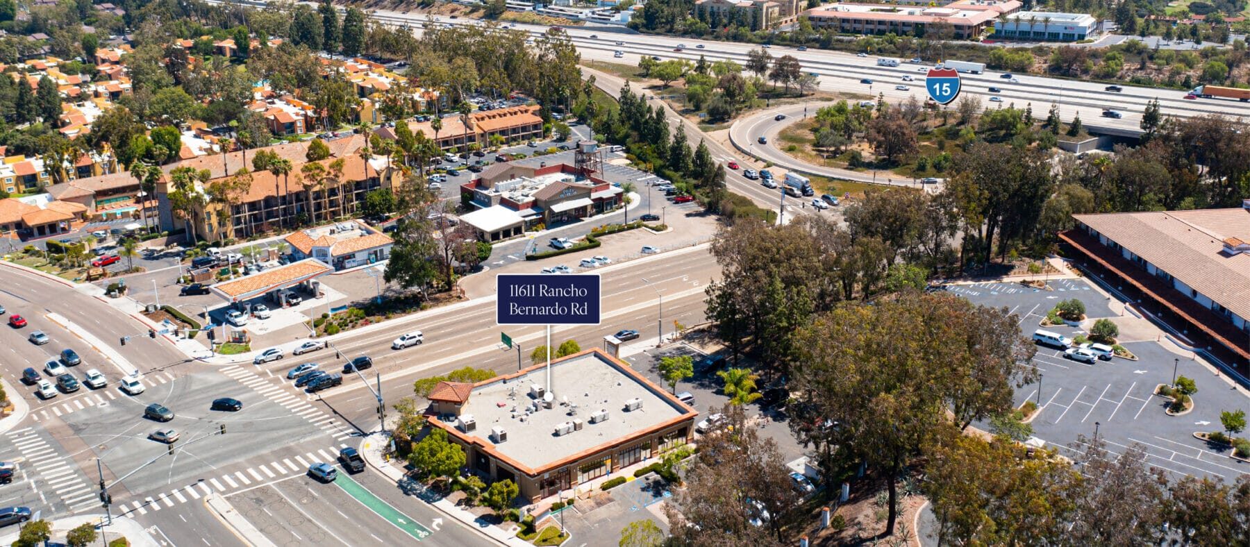 Aerial of 11611 Rancho Bernardo Rd at the corner of Rancho Bernardo Rd and Bernardo Dr. The on/off ramps for the I-15 freeway are in the near background.