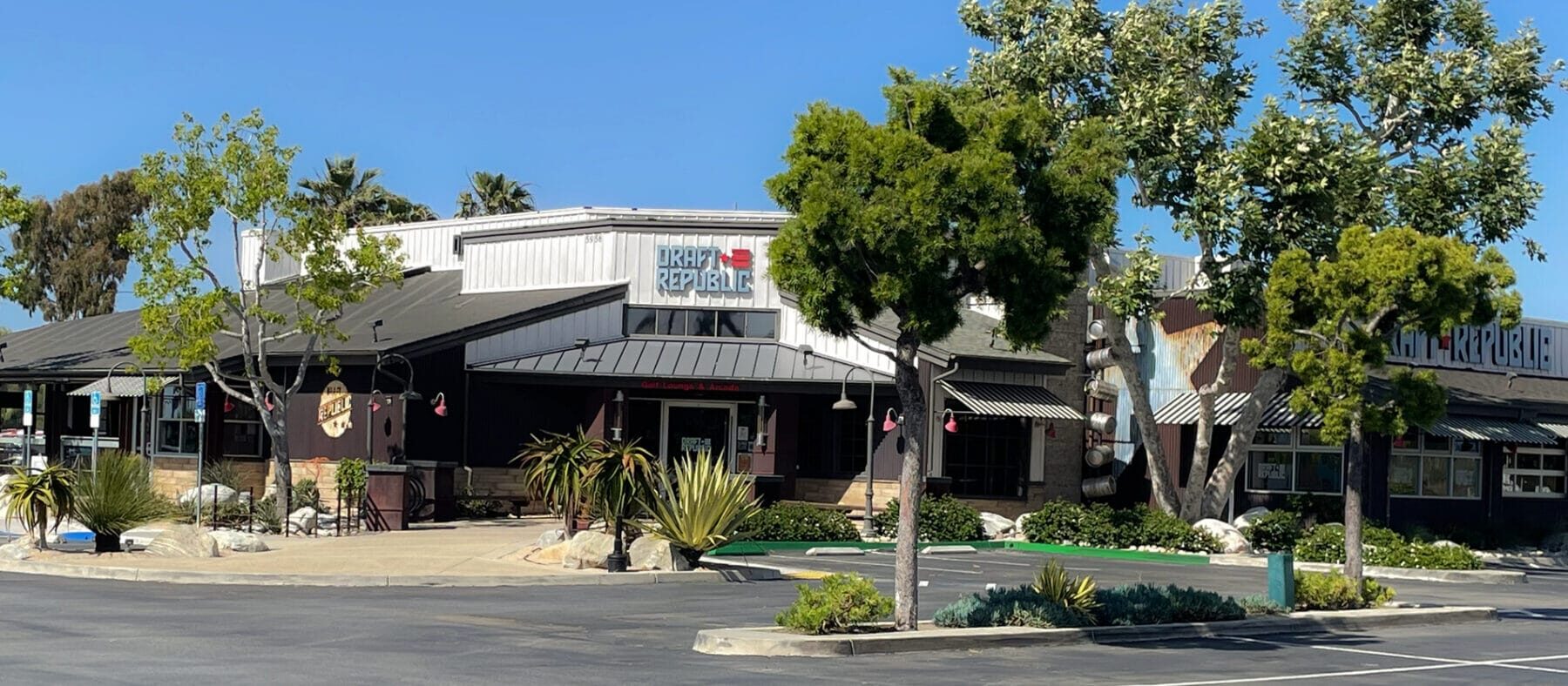 single story building of a restaurant with large trees surrounding it and a parking lot, with blue skies