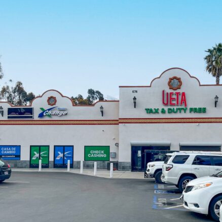 The building at 674 E San Ysidro Blvd viewed from the adjoining parking lot, suite B (Available Space) on the left and suite A (UETA Duty Free) on the right.
