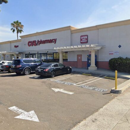 Single story, white storefront with parking lot, blue skies