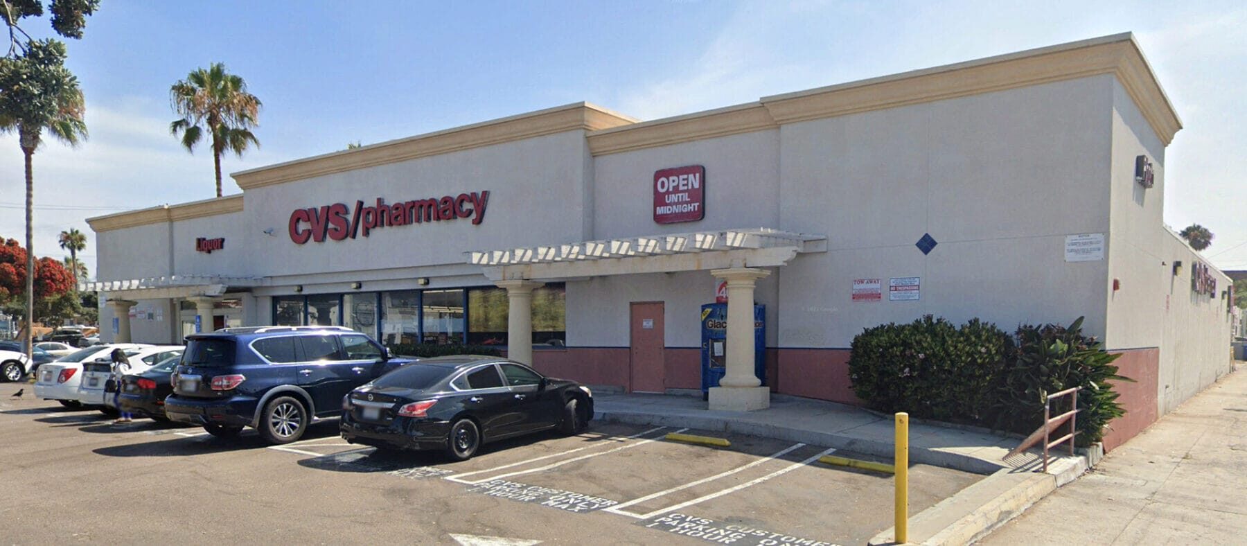 Single story, white storefront with parking lot, blue skies