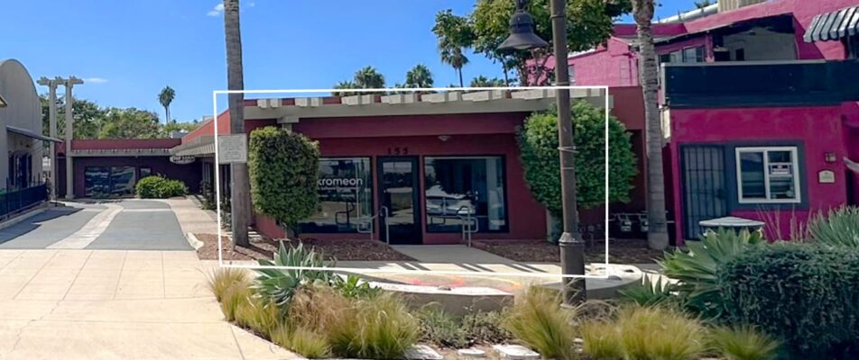 Front view of a single story red building with greenery in front and palm trees