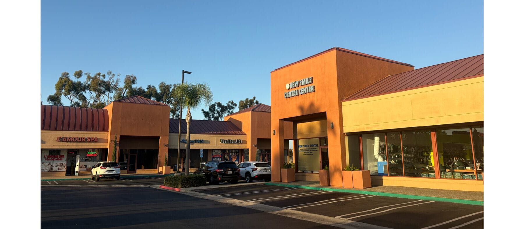 Strip mall center with tan and burnt Sienna buildings, blue sky and palm trees
